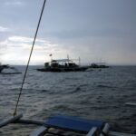 Três bancas de mergulho ancoradas em Monad Shoal sob um céu cinza de manhã cedo, vistas do convés de outro barco
