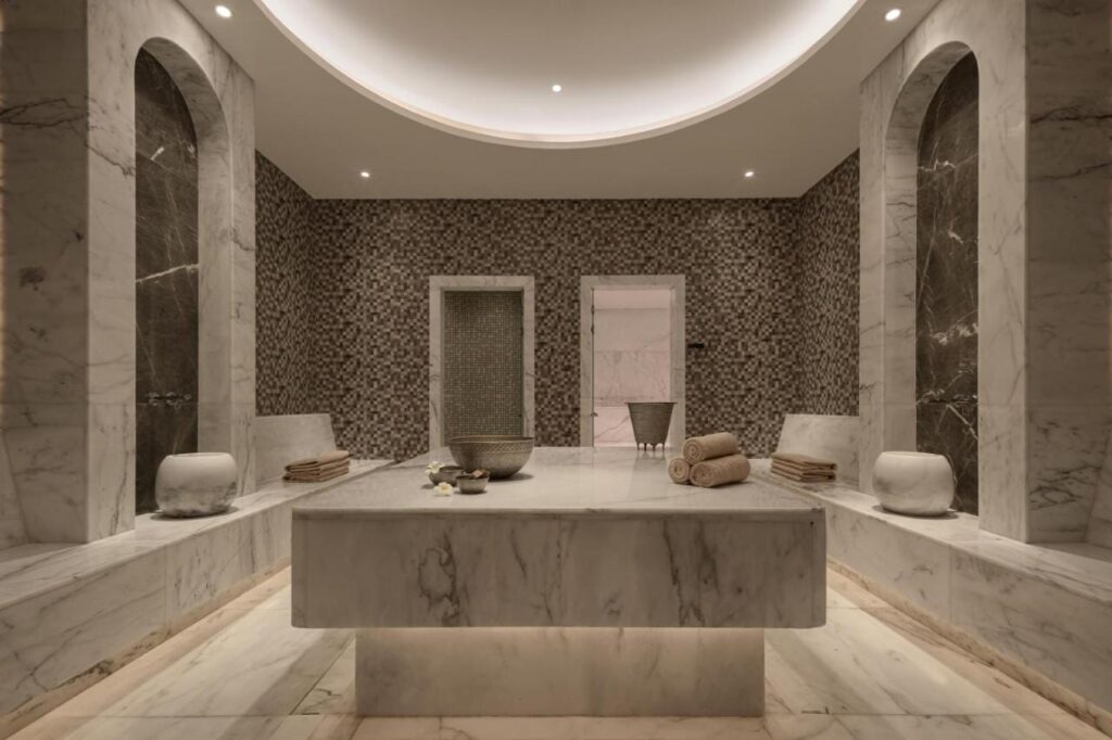Uma sala do spa do JAZ Elite Riviera revestida de mármore, com uma grande mesa de pedra no centro