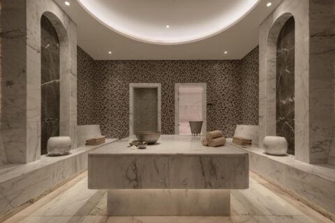 Uma sala do spa do JAZ Elite Riviera revestida de mármore, com uma grande mesa de pedra no centro