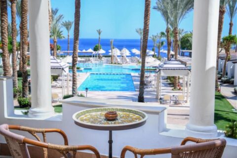 A vista de um terraço do JAZ Fanara Resort para as piscinas, as palmeiras e o Mar Vermelho
