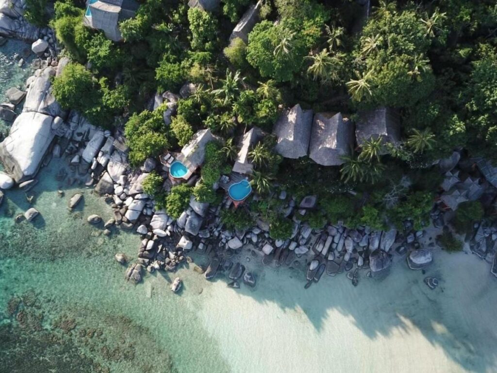 Vista aérea do Koh Tao Cabana, com chalés entre as árvores, pedras e praia de areia branca