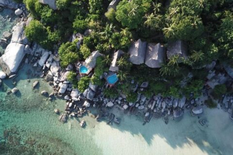Vista aérea do Koh Tao Cabana, com chalés entre as árvores, pedras e praia de areia branca