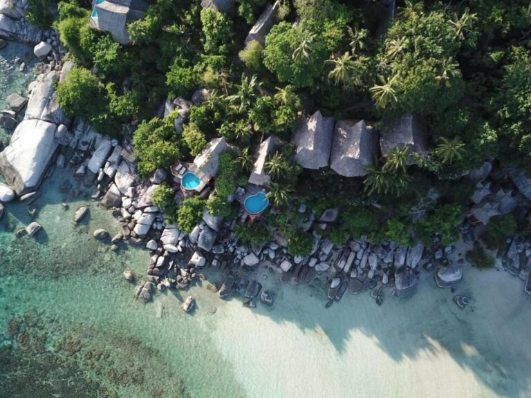 Vista aérea do Koh Tao Cabana, com chalés entre as árvores, pedras e praia de areia branca