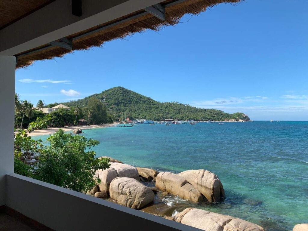 A baía e suas rochas vistas de um terraço coberto do Koh Tao Heritage, com barcos ancorados