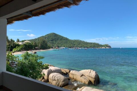 A baía e suas rochas vistas de um terraço coberto do Koh Tao Heritage, com barcos ancorados