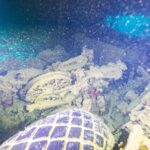 Num porão escuro do Thistlegorm, uma moto tombada atrás de um pneu de caminhão, iluminada pela lanterna