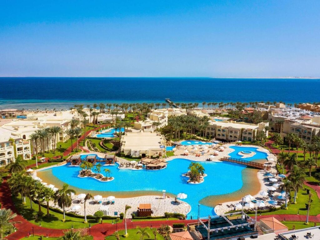 Vista aérea do Rixos Sharm El Sheikh, com piscinas em forma de lagoa, palmeiras e o Mar Vermelho