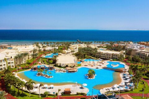 Vista aérea do Rixos Sharm El Sheikh, com piscinas em forma de lagoa, palmeiras e o Mar Vermelho