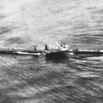 Foto de arquivo em preto e branco, tirada de um avião, de um submarino navegando na superfície de um mar encrespado, com a esteira ao longo do casco e a torre no centro.