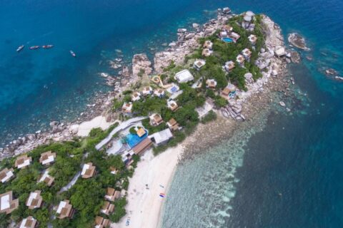 Vista aérea do Sai Daeng Resort, com bangalôs numa ponta de pedras, piscinas e praia de areia