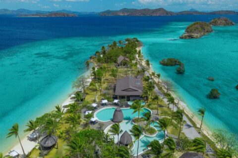 Vista aérea do Two Seasons Coron, com piscinas e palmeiras numa estreita faixa de terra entre duas praias